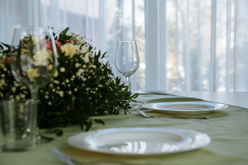 in a bright room, with daylight, a festive table is decorated, with plates and glasses