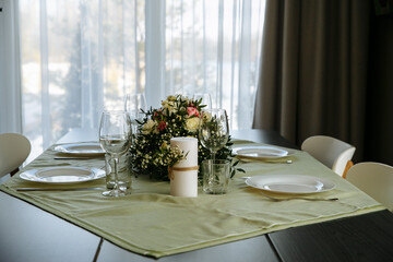 in a bright room, with daylight, a festive table is decorated, with plates and glasses
