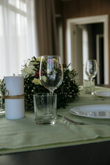 in a bright room, with daylight, a festive table is decorated, with plates and glasses