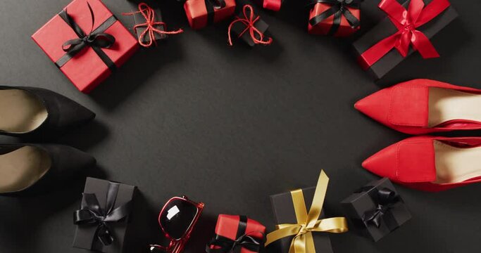 Red and black shoes, gift bags and gift boxes on black background with copy space