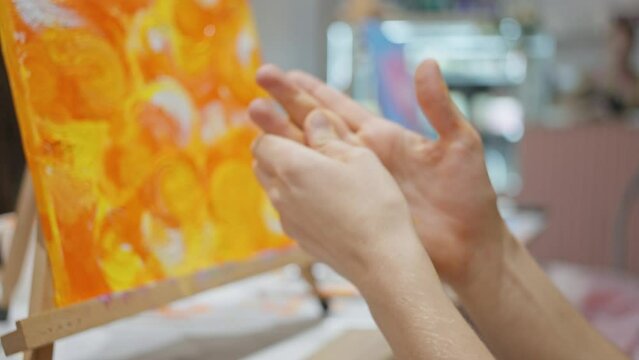 Female hands close-up, the artist wipes her hands from the paint