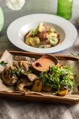 rosted half chicken with fried yellow potatoes and arugula salad on wooden plate on the table
