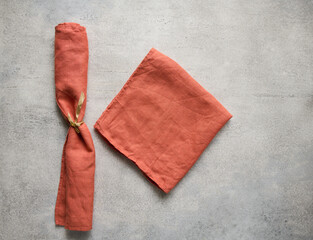 Terracotta folded linen napkins on gray concrete table with copy space, top view