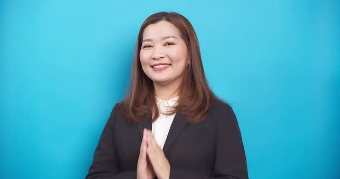 Beautiful Thai businesswoman in a black suit guests Sawadee with a smile on blue background