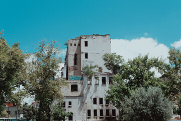 Fototapeta premium Damaged white building among trees, open blue sky, retro color palette, Eminonu karakoy old streets and structures, abandoned building idea