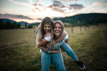Cute blonde friends are having fun during an summer evening photoshoot with holi powder.