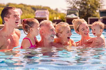 Smiling Multi-Generation Family With Baby Boy On Summer Holiday Relaxing In Swimming Pool