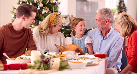 Multi-Generation Family Celebrating Christmas At Home Eating Meal Together Around Table
