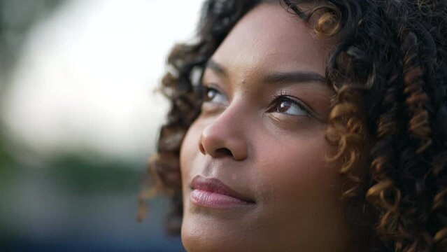 Pensive millennial African American young woman closeup face looking at sky. Thoughtful female person