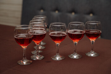 a row of glasses with red wine on the table in the kitchen