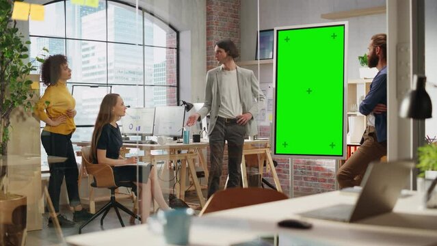 Stylish Young Project Manager Talking on a Team Meeting in Creative Agency Conference Room. Colleague Showing Business Plan Presentation on Green Screen Mock Up Chroma Key Monitor.