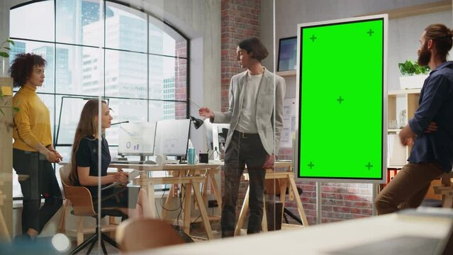 Young Marketing Specialist Leading a Brainstorm Session with a Team in Creative Office Meeting Room. Project Manager Showing Presentation on Green Screen Mock Up Chroma Key Display.