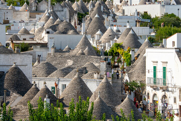  typical trulli houses in Alberobello, Puglia, Italy. Traditional symbols are painted on the conical roofs. A trullo is a traditional Apulian stone dwelling in Itria Valley.
