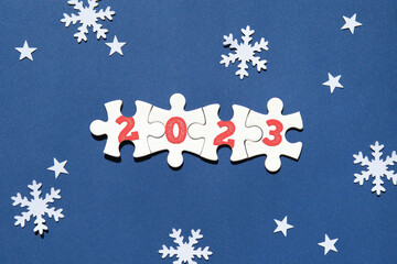 Jigsaw puzzle with numbers 2023 and caption text Happy New Year. Flat lay, top view on dark blue...