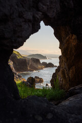 Impressive landscape of cliffs and sea at sunset through a hole in the rock. Caravia, Asturias,...