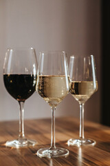 House party. Three glasses of red and white wine on the table in the living room in the rays of the setting sun