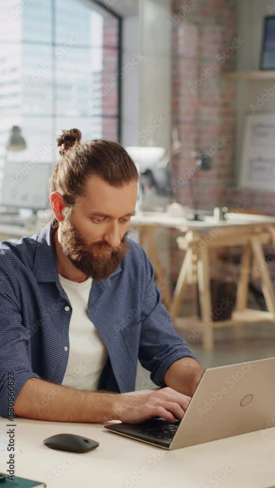 Poster vertical screen: handsome long-haired bearded manager sitting at a desk in creative office. young st