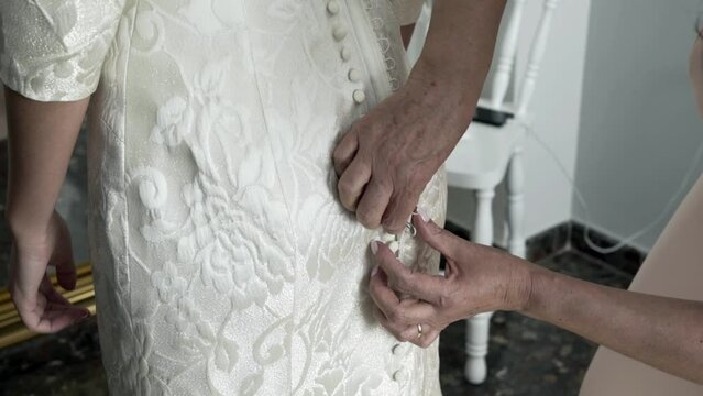 bridesmaid fastening wedding bride dress on the hip, close up view. Helping the bride to get ready for the event.
