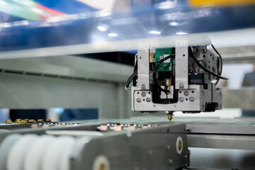 Automatic SMD pick and place machine during work - assembly of computer circuit board at factory. Automated technology, industrial, robotic, electronic, production, manufacturing concept