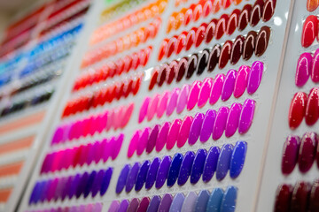 Set of many colorful palletes of gel nail polishes on counter of make up store, manicure salon, exhibition - close up view. Fashion, care, cosmetic, beauty, makeup and glamour concept