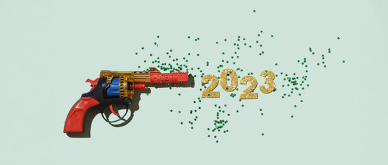 Creative composition with a toy gun and numbers of the new year 2023