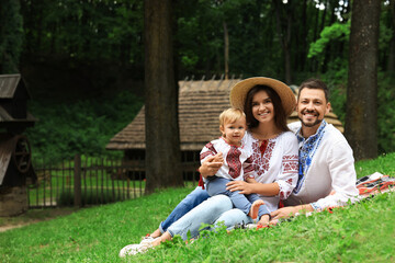 Fototapeta premium Happy family in Ukrainian national clothes on green grass outdoors