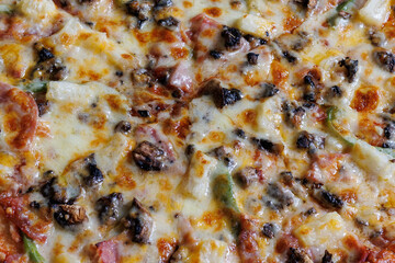 close up of cheesy pizza with mushrooms green pepper and ham