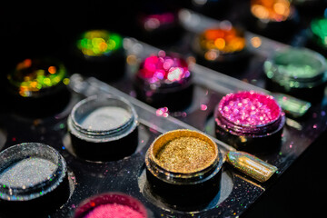 Samples of cosmetic nail art glitter in row on counter for sale in make up store, manicure salon, exhibition. Glamour, fashion, make up, beauty and skincare concept