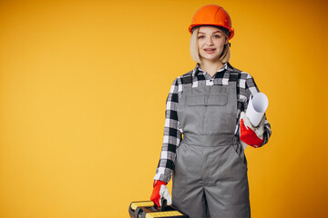 Woman builder holding tool box and wearing helmet