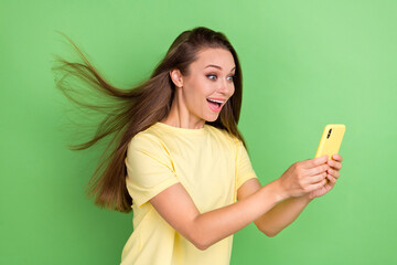 Portrait of impressed speechless open mouth cute girl with long hairdo wear yellow t-shirt read notification on green color background