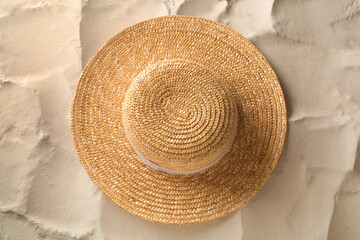 Fototapeta na wymiar Stylish straw hat on sand, top view