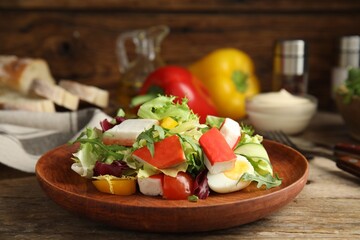 Delicious salad with crab sticks and lettuce on wooden table