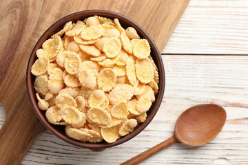 Bowl of tasty corn flakes and spoon on wooden table, top view