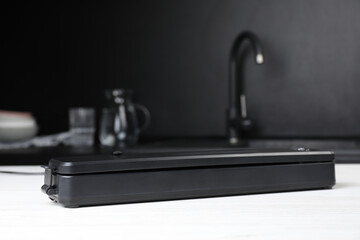 Sealer for vacuum packing on white wooden table in kitchen