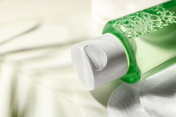 Bottle of micellar cleansing water and cotton pads on white table, closeup. Space for text