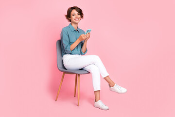 Full size photo of young adorable pretty cute nice perfect lady sitting cafeteria chair advert positive using smartphone app online delivery isolated on pink color background