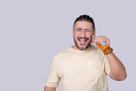A smart guy in his 30s enjoying a bottle of light beer. Making an ahhh exclamation. Isolated in a gray background.