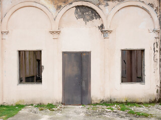 Fototapeta na wymiar Old abandoned building with rusty iron door and broken windows. Abandoned railway station