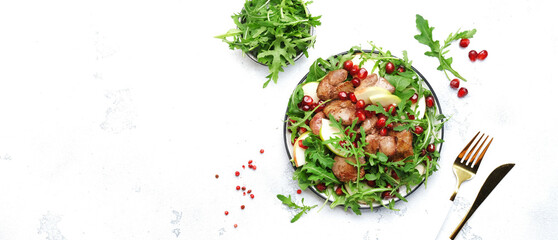 Healthy fresh salad with chicken liver, apple, pomegranate and arugula. White kitchen table...