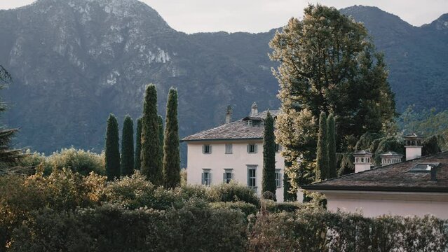 A look from far away onto hidden famous Villa Balbiano at lake como italy luxury wedding venue location surrounded by alp mountains - cinematic