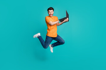 Full size photo of jumping guy using netbook impressed e commerce web discount isolated on cyan color background