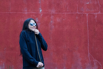 Women closing sweater in front of red wall