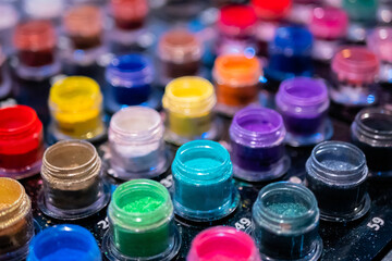 Transparent jars with colorful mineral eyeshadow in row on counter for sale in makeup store,...