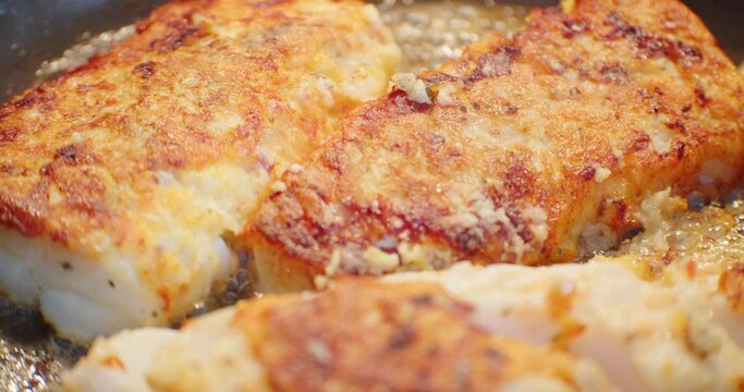 A cod fish steak frying in a frying pan close-up. Cooking fish in the hot oil at restaurant.
