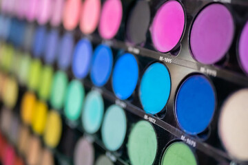 Pallet with vibrant eyeshadow for make up in cosmetic store - close up view. Makeup, beauty, fashion and glamour concept