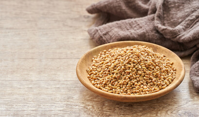 fenugreek seed in wood plate on wooden table background. fenugreek seeds background                                                                    
