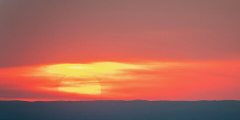 Large sun hidden by clouds in the sky at sunset