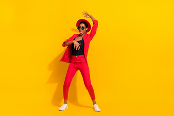 Photo of pretty beautiful short hair person dressed red suit cap dark eyewear dancing isolated yellow color background