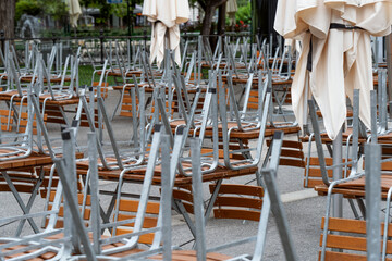 Closed street cafe. Tables with overturned chairs.