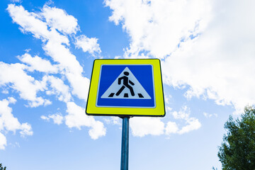 Blue and white pedestrian crossing sign on the sky background